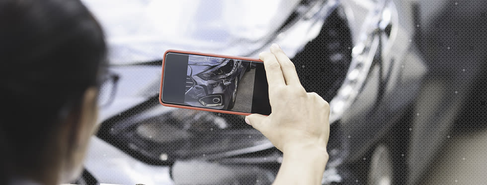 Person uses cell phone to take picture of vehicular damage.